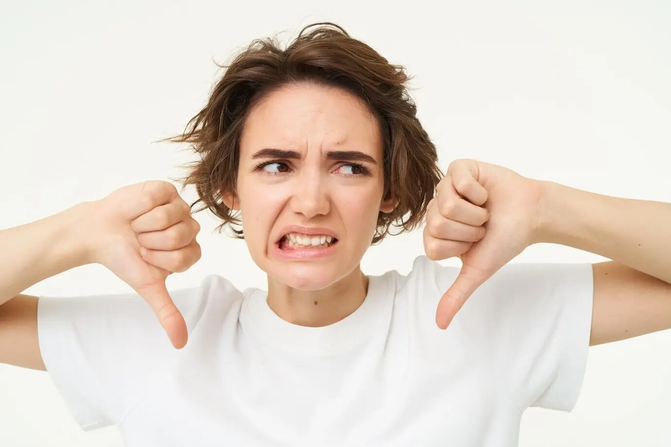 Крупным планом разочарованная молодая клиентка показывает жест неодобрения — большой палец вниз — с гримасой неловкости.